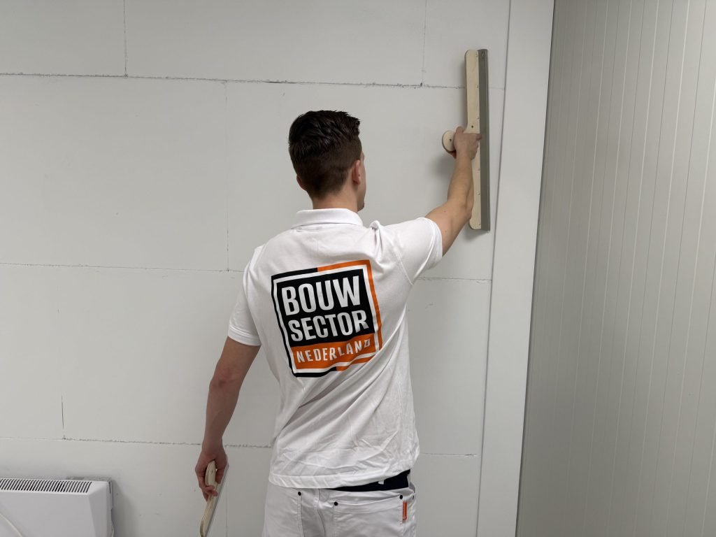 Stukadoor van Bouwsector Nederland werkt met een brede spaan een naad in een plaatwand af